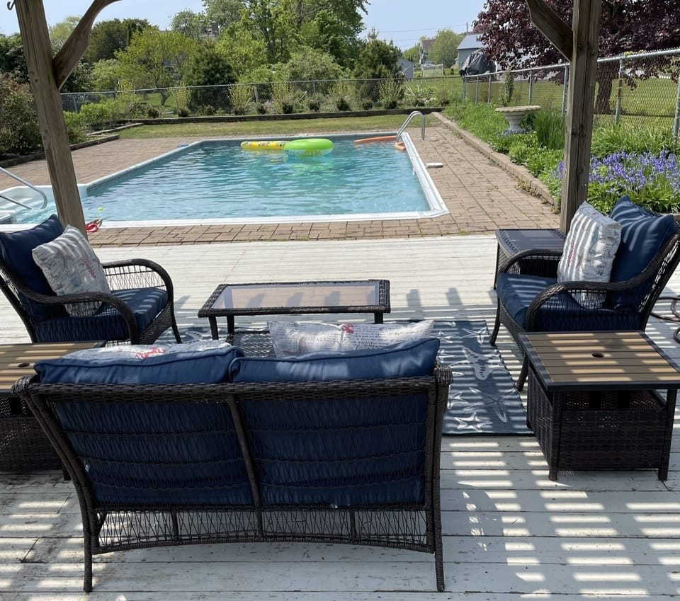 In-ground saltwater pool with spacious deck, sitting area and dining tables.