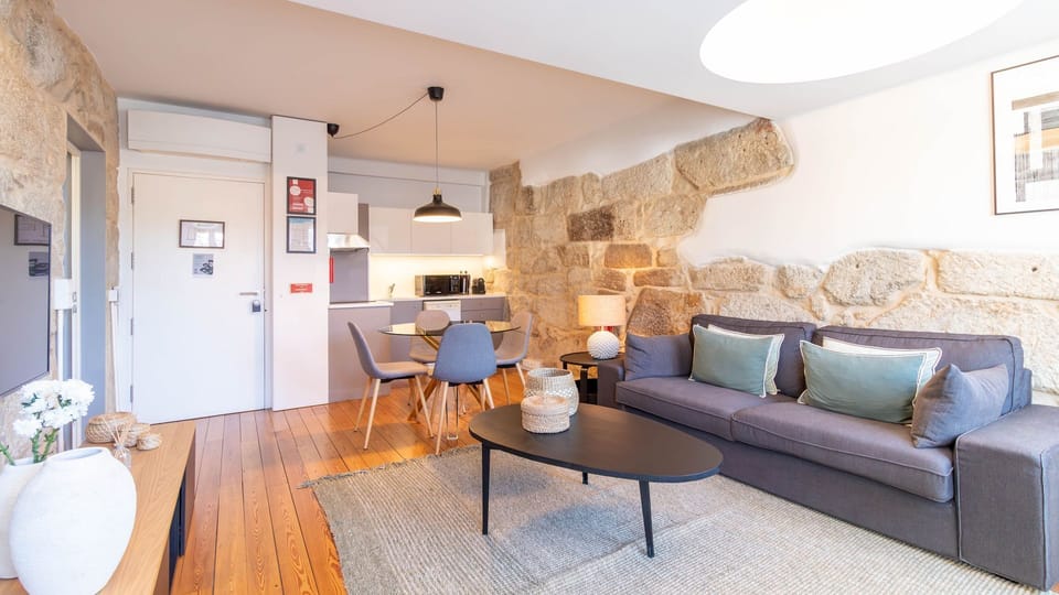 Relax in the stylish open-plan living area, where contemporary comforts meet historic charm with exposed stone walls and warm wooden floors. The integrated kitchen and dining space invite you to enjoy home-cooked meals or simply unwind after a day of expl