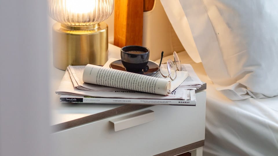 Enjoy a quiet morning with coffee and a good read by the warm glow of your bedside lamp, creating a cozy and inviting start to your day. This little corner offers a peaceful moment of solitude.