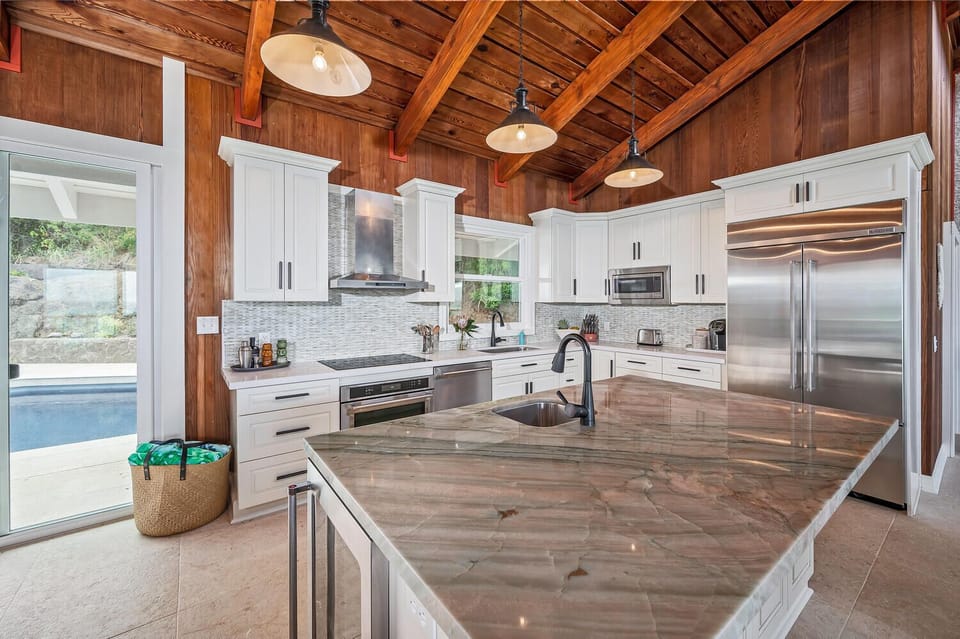 Gourmet kitchen with modern appliances and travertine countertops.