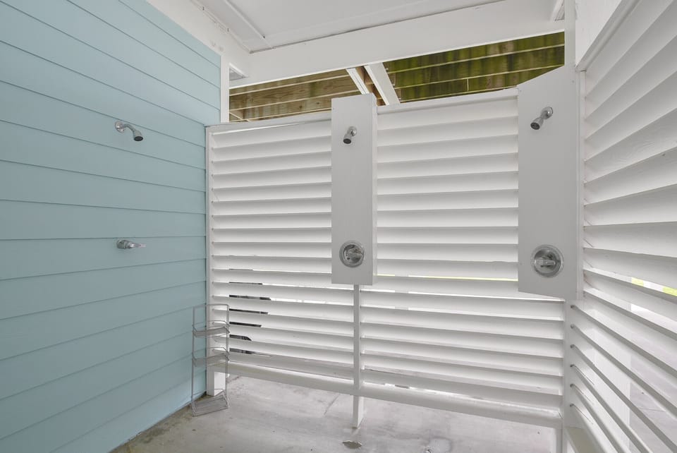 Outdoor shower with three shower heads and hot and cold water.