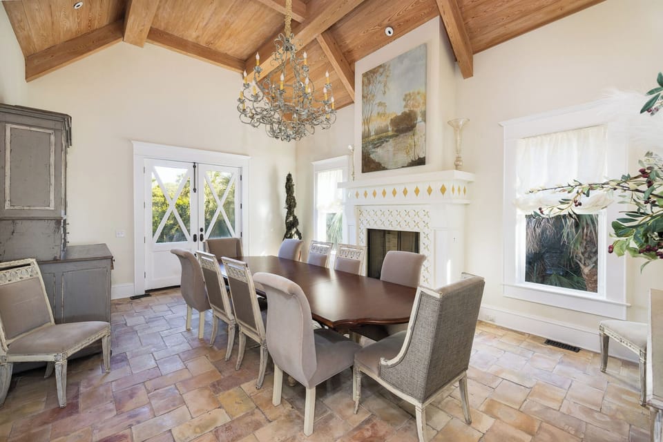 Just behind the kitchen is the grand dining room with high vaulted ceilings and a fireplace