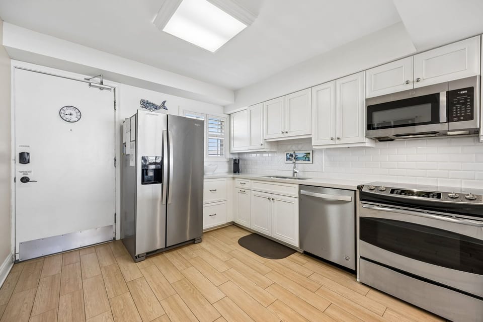 Your kitchen features modern stainless-steel appliances, bright white cabinetry, and a skylight that floods the space with natural light—ready for preparing memorable meals together.