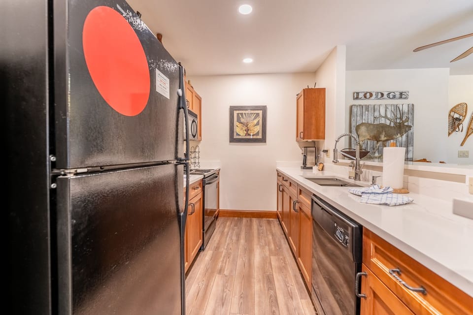 Your fully equipped galley kitchen features stainless steel appliances and warm wood cabinetry, perfect for preparing mountain lodge meals.