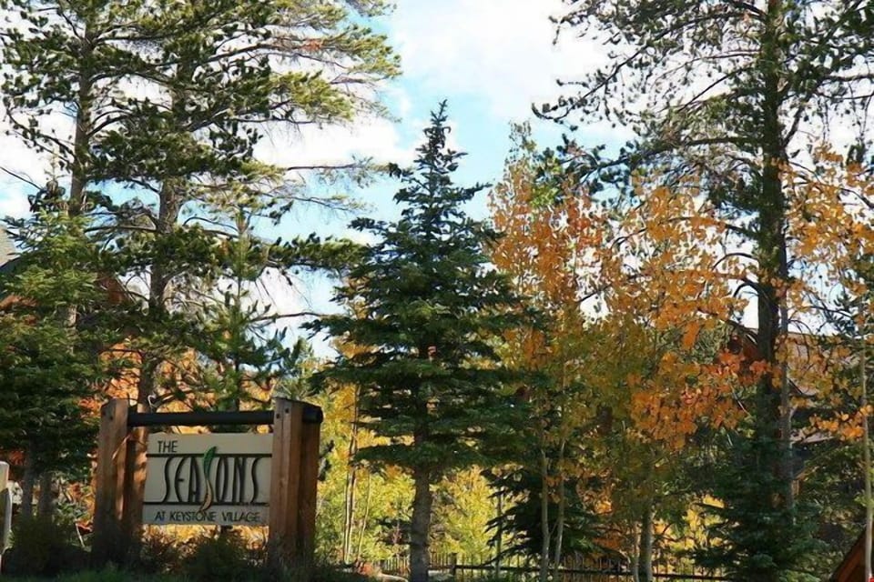 The Seasons at Keystone Village sign is framed by vibrant fall foliage, showcasing the resort's natural beauty throughout the seasons.