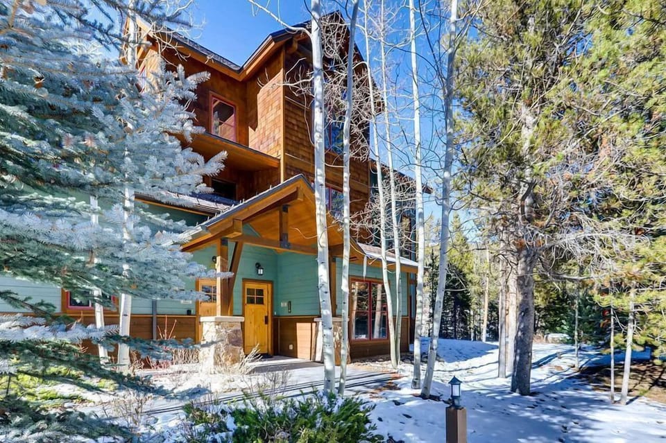 The inviting facade of The Seasons, beautifully surrounded by snowy landscapes and tall trees, offers a warm alpine retreat.