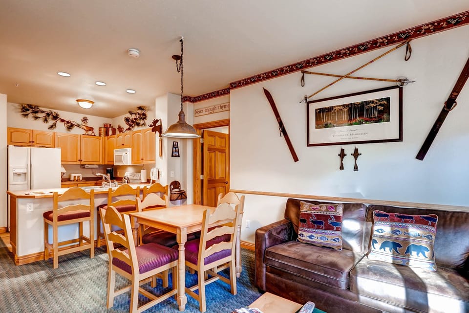 The cozy living area features mountain lodge decor, complete with charming artwork and rustic furnishings, inviting relaxation after a day of adventure.