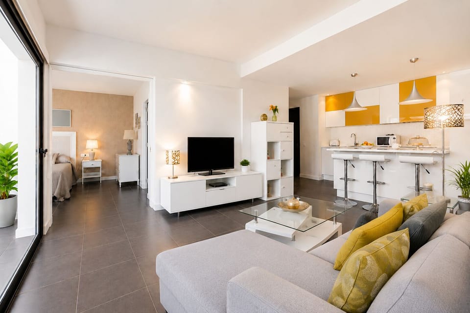 Elegante salón con cocina abierta, iluminación cálida y decoración moderna para una estancia acogedo