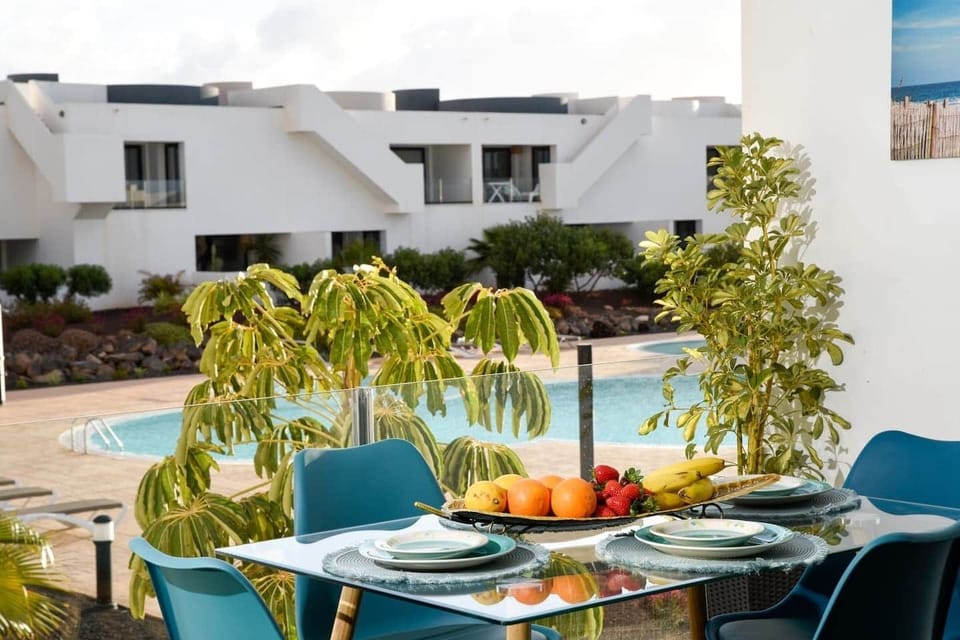 Terraza privada con comedor exterior y agradables vistas a la piscina y jardines del complejo.