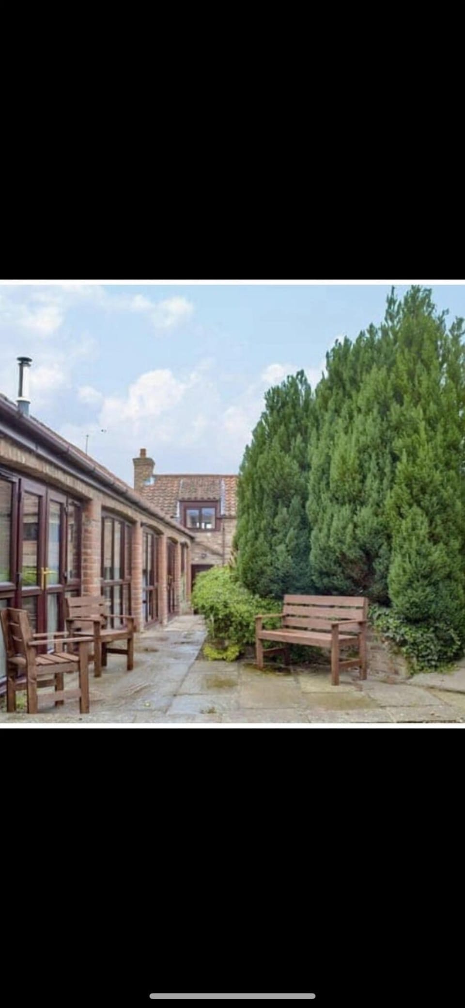 Small private patio area with table, chairs & BBQ, leading onto shared garden 