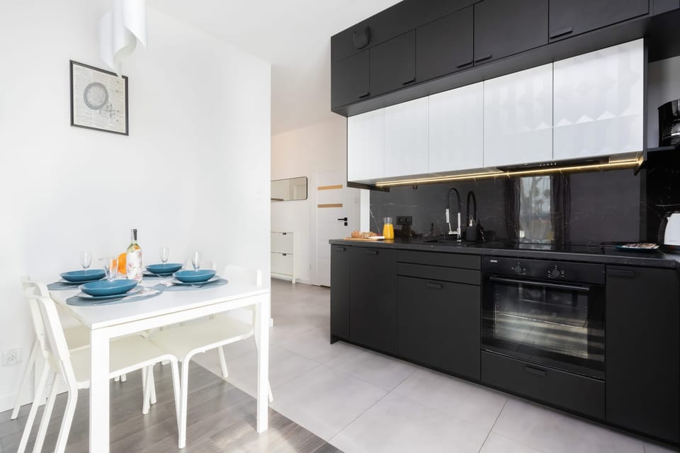 A sleek, modern kitchen with black and white cabinets, an adjoining dining area with a set table for two.