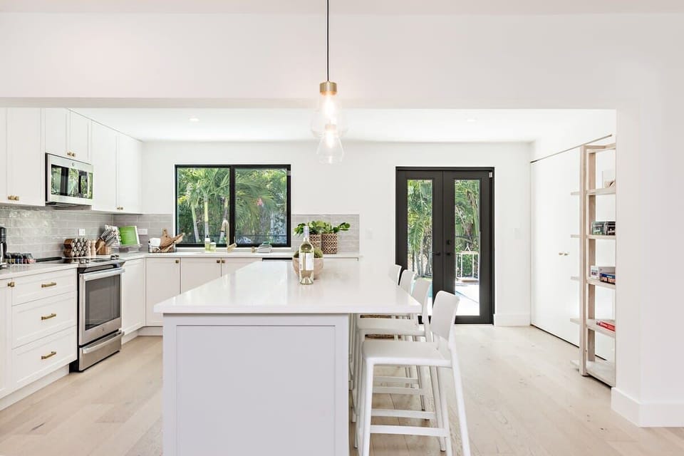 Modern kitchen with a large island and natural light from garden-facing windows and doors.