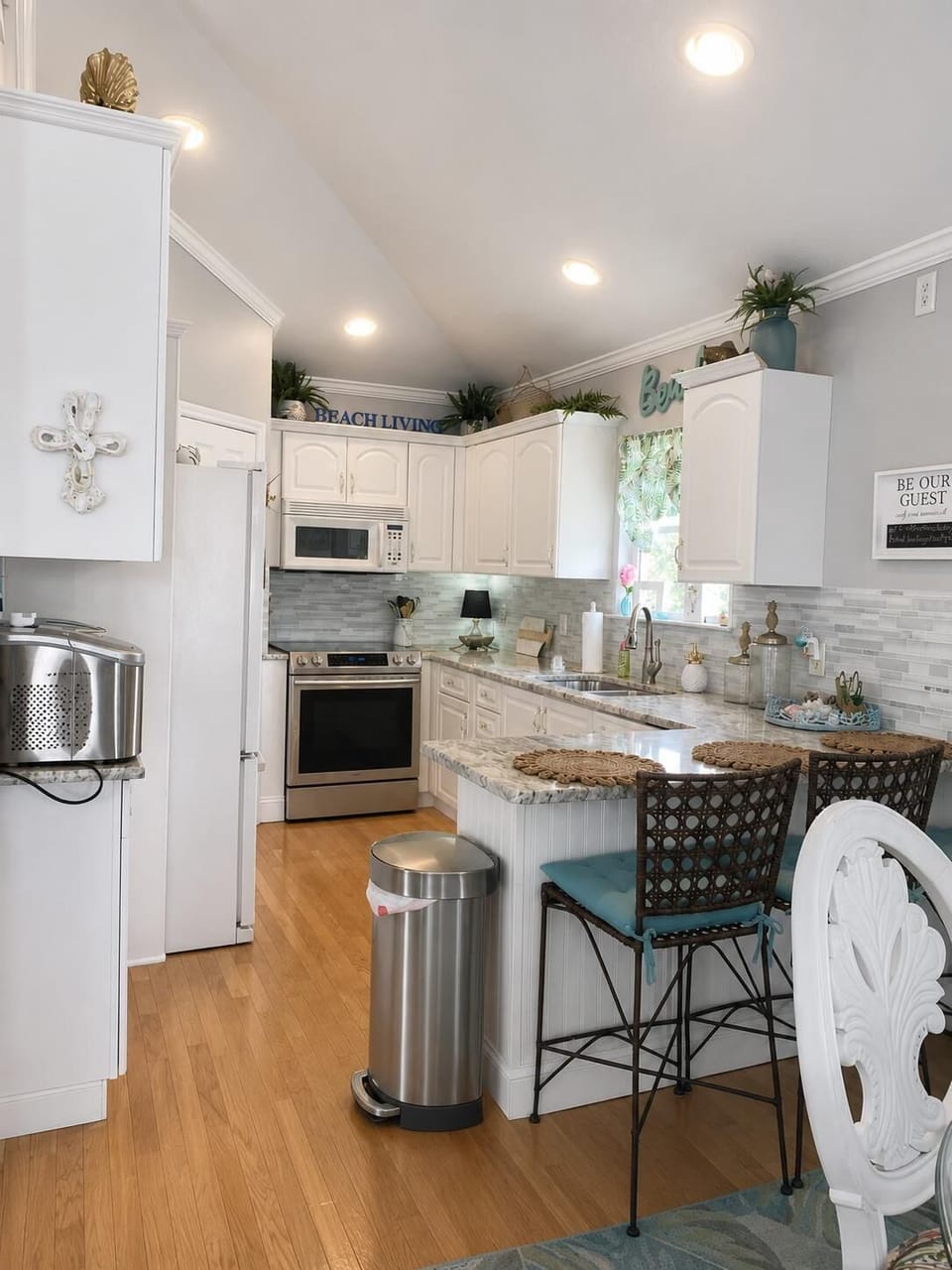 White cabinetry and gray marble countertops surround a stainless steel stove and refrigerator in the kitchen.