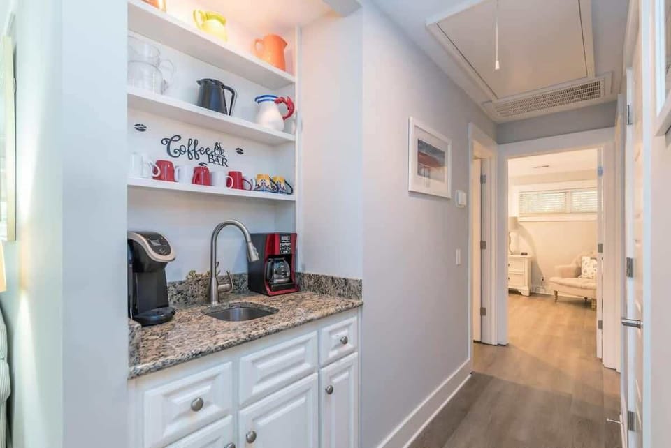 Bright coffee nook: Keurig + drip brewer, sink, granite counter, stocked mug shelves