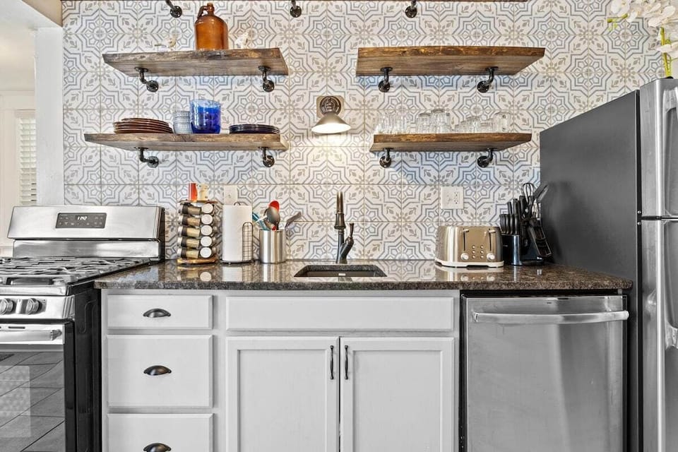 Stylish kitchen featuring open shelving and a stunning patterned backsplash that adds character to the space.
