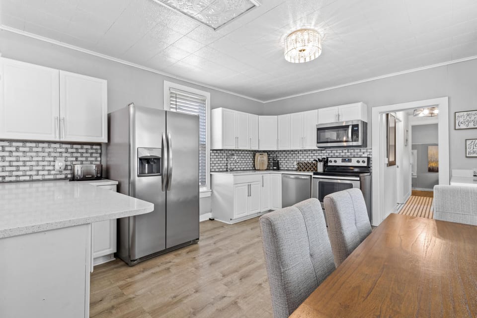 Spacious, fully equipped kitchen featuring stainless steel appliances, quartz counters, and a large dining area—perfect for cooking before heading out to explore Westport or hop on the KC Streetcar.