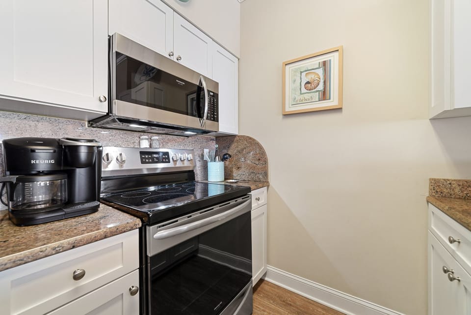 This fully functional kitchen boasts stainless steel appliances, sleek countertops, a decorative backsplash, and ample cabinet storage, ideal for everyday cooking and entertaining.