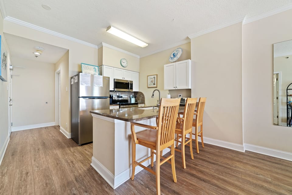 Extra sleek and sophisticated kitchen featuring a striking island with a stone countertop and comfortable bar stools. eating