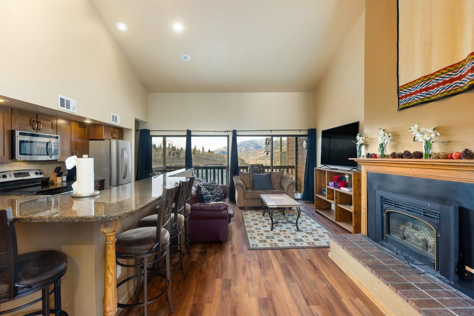 Spacious living area with large smart TV, gas fireplace, hardwood floors and ample seating.