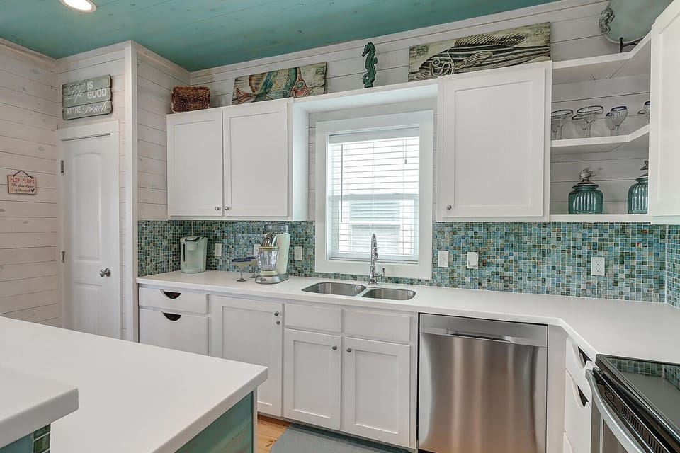 Your coastal-inspired kitchen awaits with charming sea-glass backsplash and stainless appliances ready for your culinary adventures.