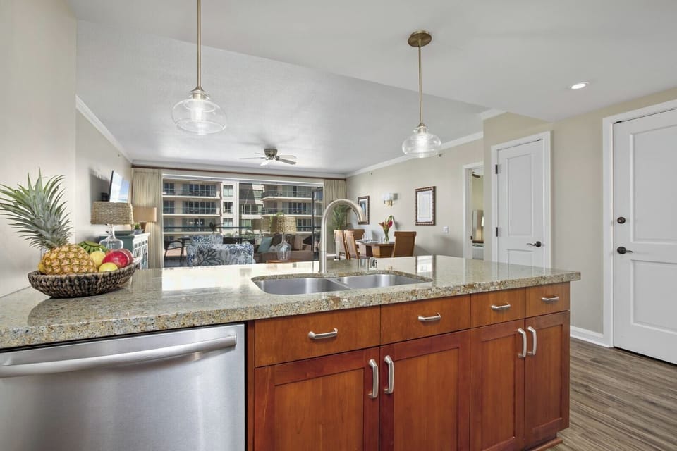 Granite kitchen island opens to airy living room and tropical views.