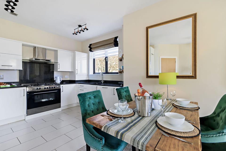 Kitchen and living area with a double sofa, two arm chairs, TV, and dining table