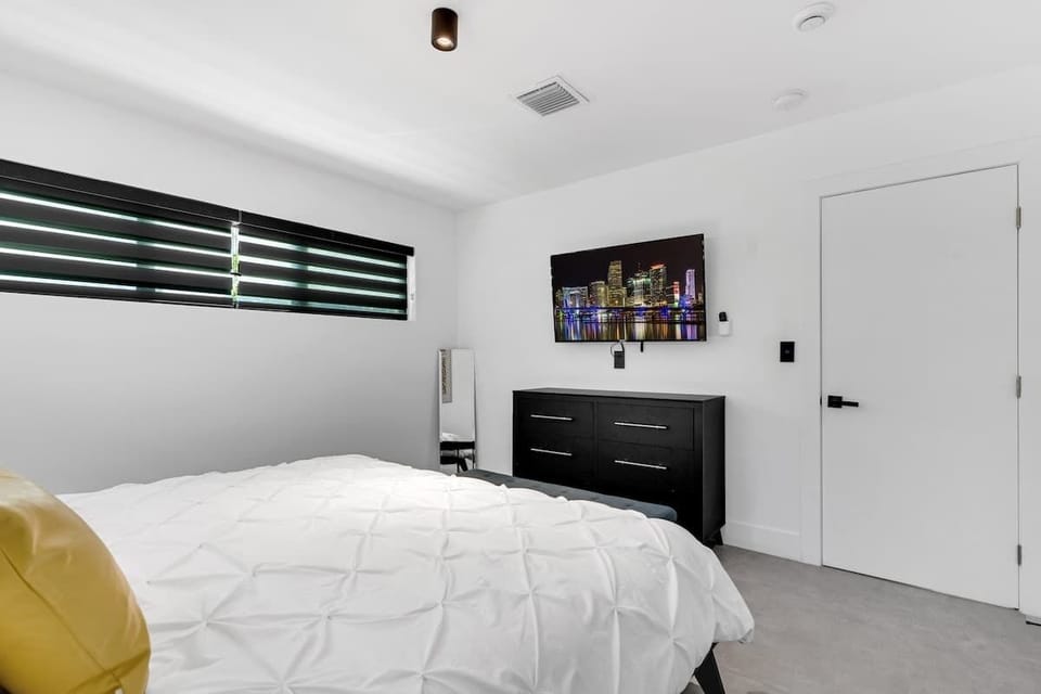 "Kick back in this bright, modern bedroom with cozy bedding, smart TV, and sleek design—perfect for couples, solo travelers, or remote workers booking a stylish vacation rental."