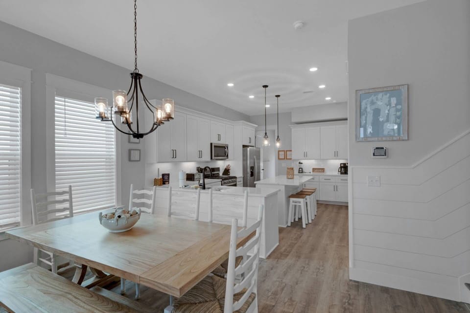 The dining area features a large farm house table with seating for up to 8 people, and an additional 4 stools at the kitchen island.