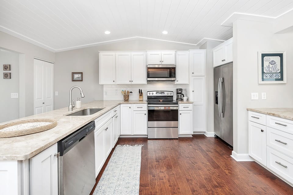 Bright, open Kitchen with white cabinets and stainless steel appliances