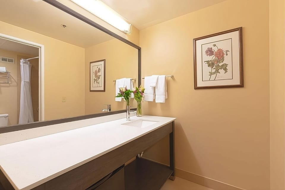 Refresh at a sleek vanity with bright mirror lighting and towels.