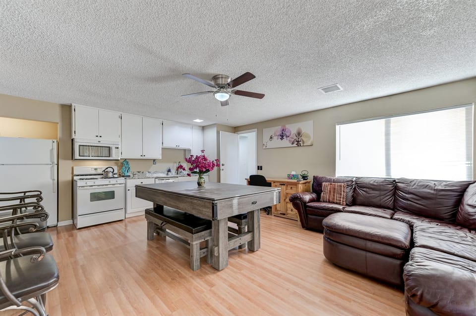 Living room 2 includes a kitchenette, leather couch, extra seating, a desk, 86 inch tv with Youtube TV, and a large dining table. The dining table converts to a pool table and ping pong table.