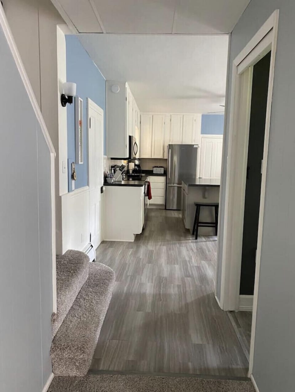 Entryway from living room to kitchen, half bathroom on right