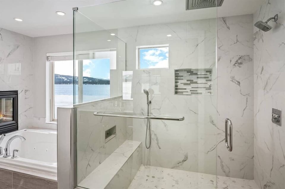 Primary bathroom with custom tiled shower, jetted tub, and gas fireplace