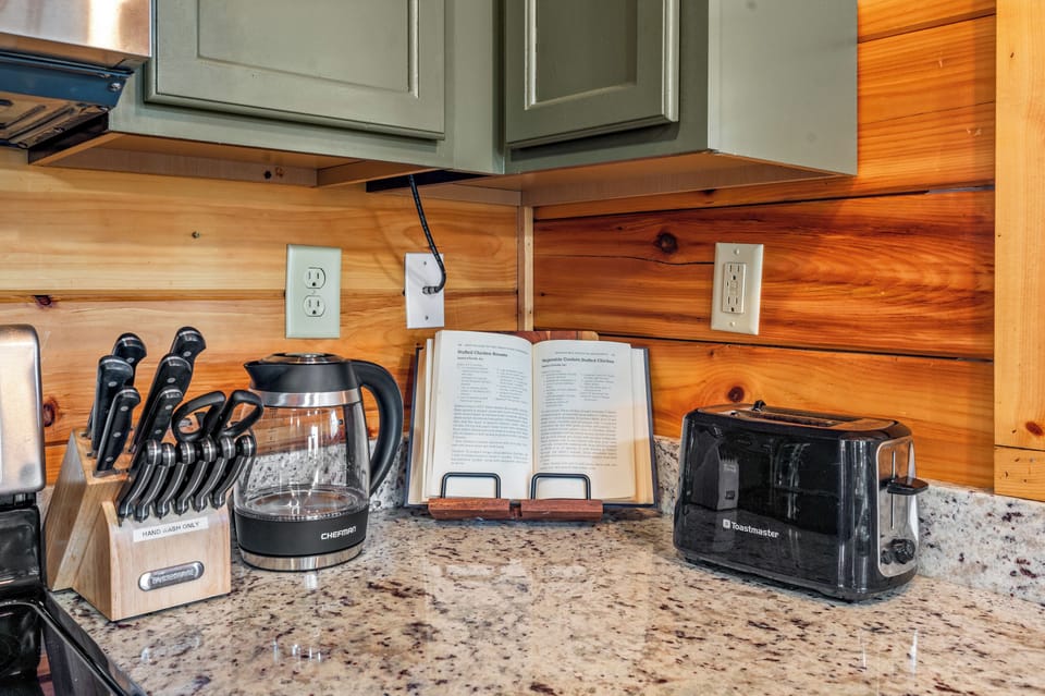 A hot water kettle and cook book are ready for use,in the fully stocked kitchen