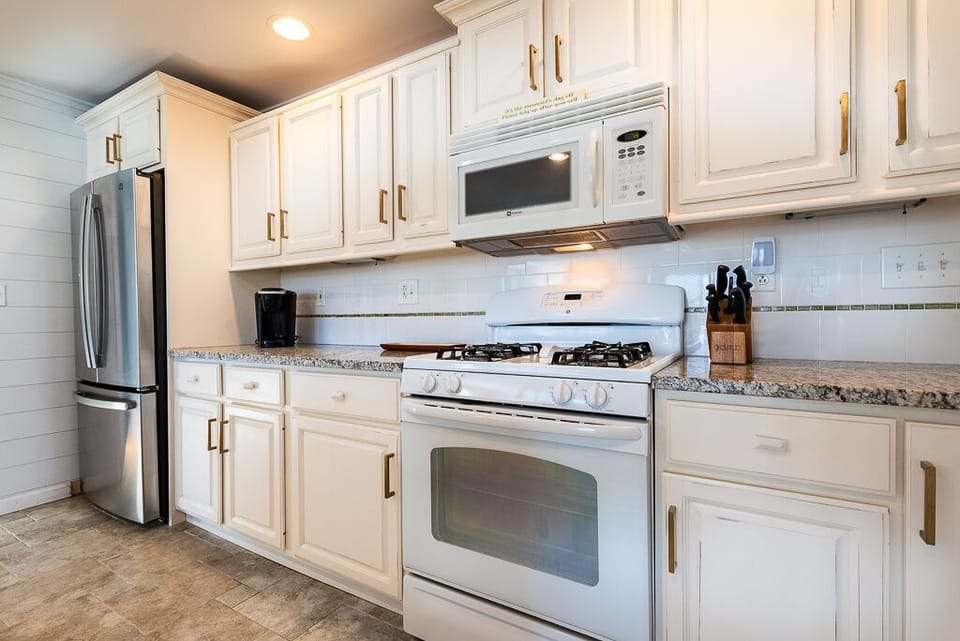 Kitchen with gas range, Keurig, microwave and stainless steel refrigerator with chilled water inside