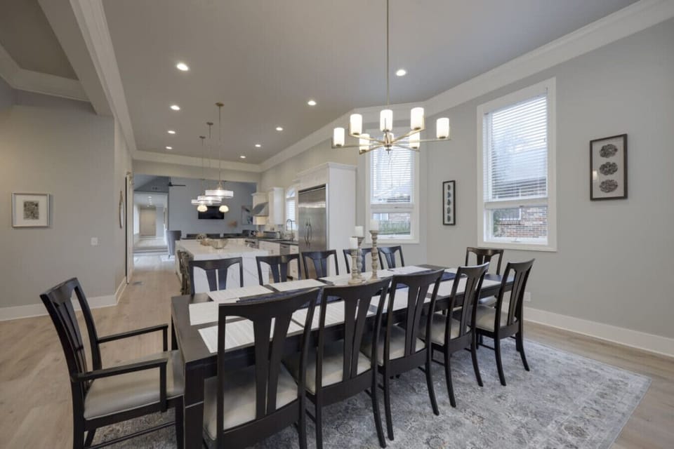 Formal dining area with a long table, black chairs, and a chandelier
