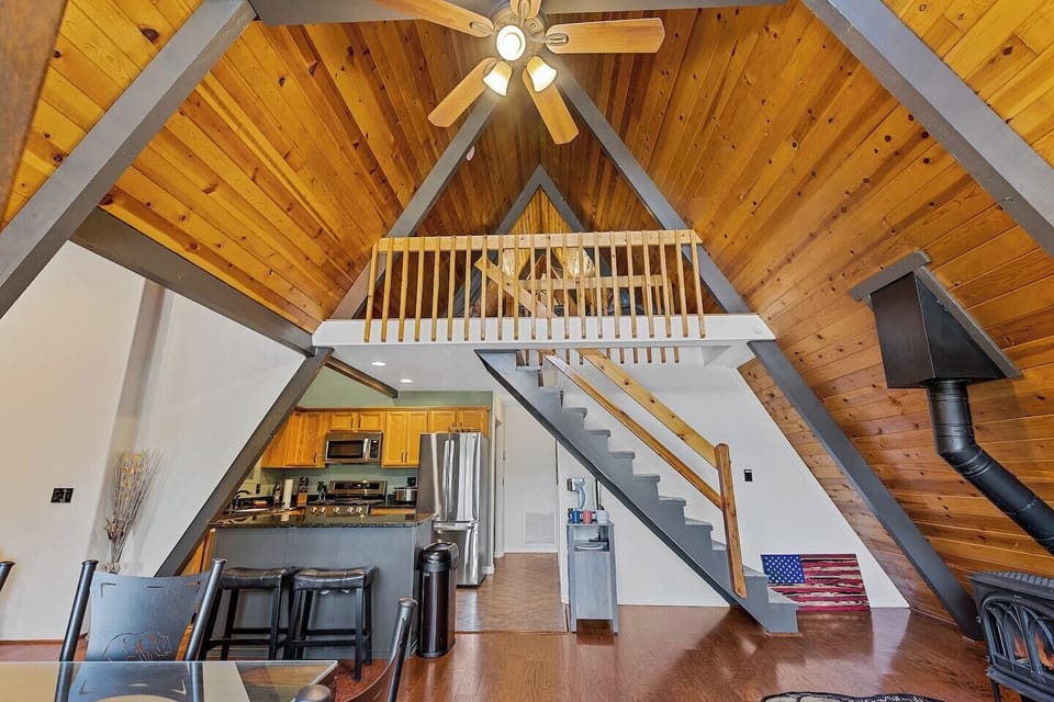 The iconic A-frame great room features soaring vaulted wood ceilings, an open loft, and a spacious open-concept layout, creating an unforgettable mountain retreat filled with rustic charm and modern comfort.