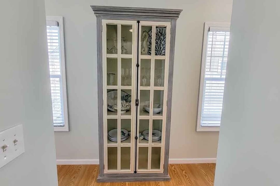 Cuiro cabinet stocked with bar glassware and serveware in main hallway
