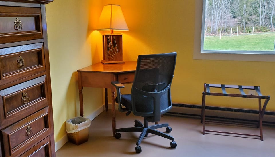 Workspace in large bedroom with wifi, power strip, and ergonomic chair.