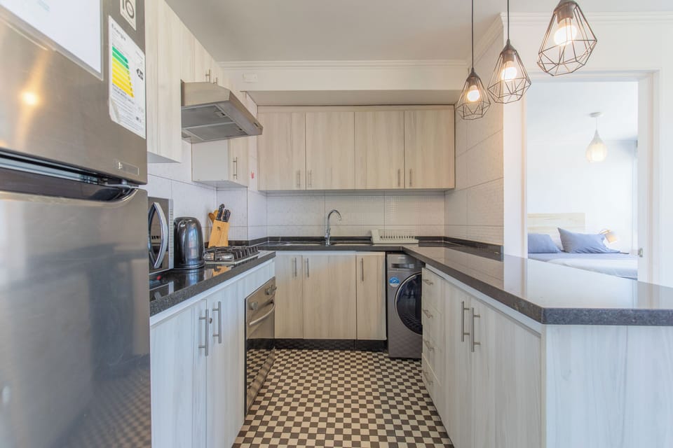 Cocina equipada con horno, encimera, microondas y refrigerador.