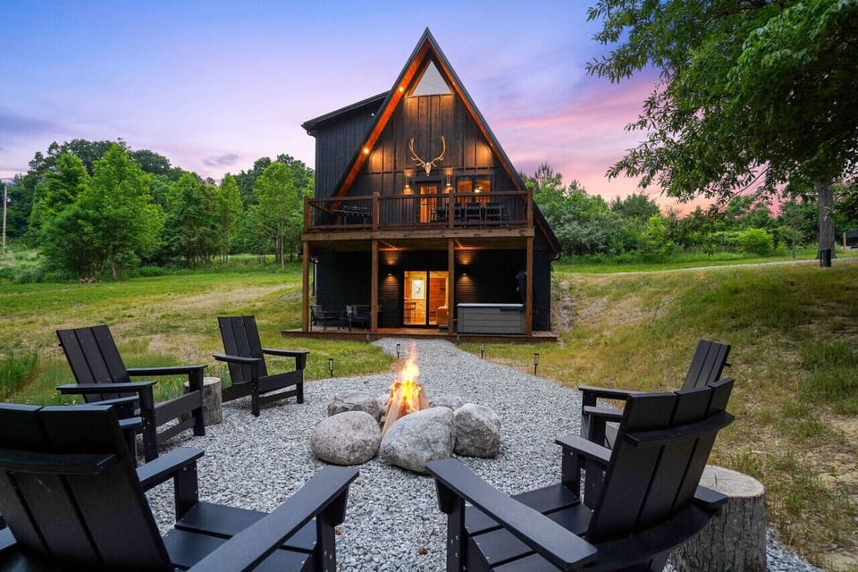 This is a view from the backside of the cabin in the summer  which shows off all three levels of the cabin: Walk-out basement with deck, main level with deck, and loft up above.