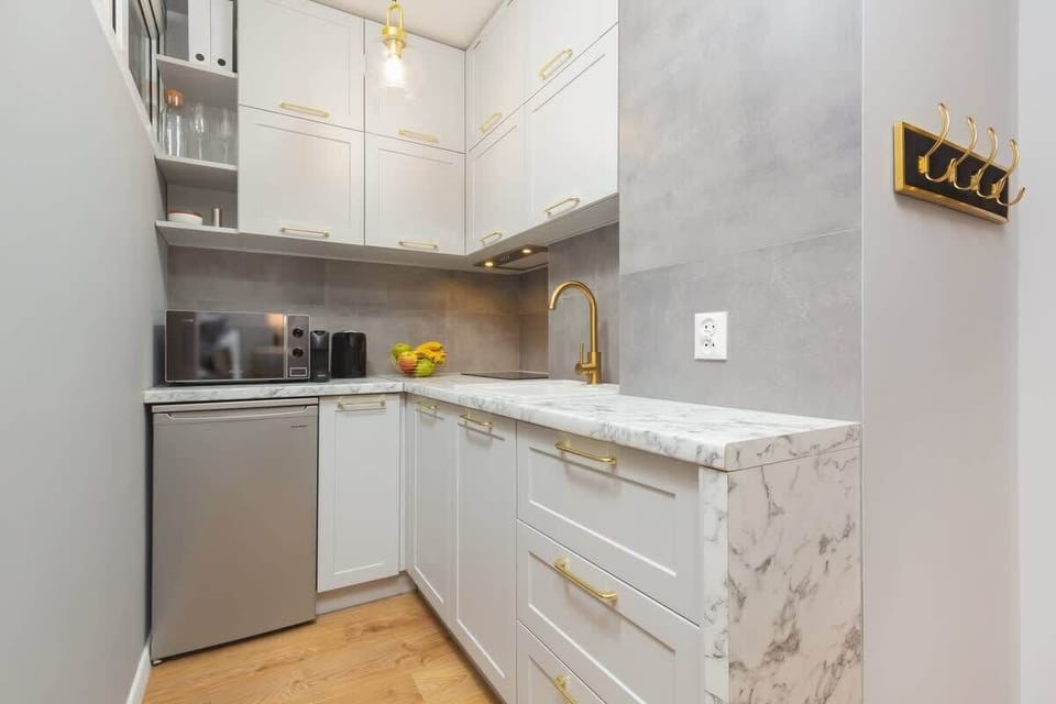Fully equipped kitchen with white cabinets, marble countertops, and modern appliances.
