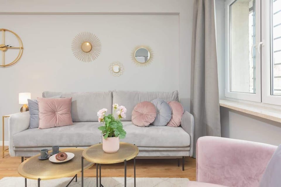 Living room view with a pink armchair, coffee table, and round decorative elements on the wall.
