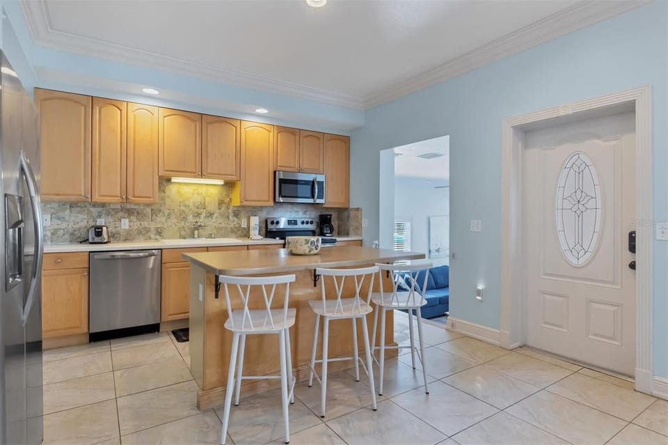 Kitchen with bar counter seating, stainless appliances, and cabinetry