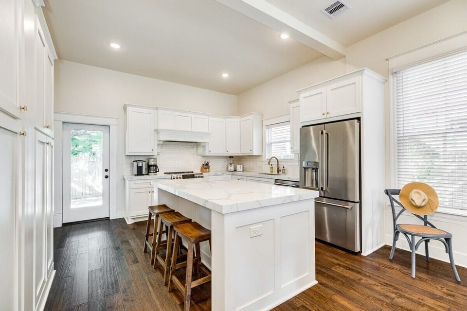 The beautiful kitchen island with marble top has seating for three and plenty of room to prep your meals and serve in style. We have more glasses, plates and utensils than you could ever need!!