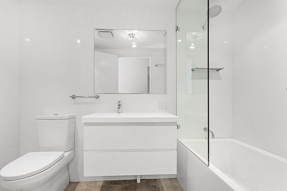 Main bathroom with shower over the bath and toilet.