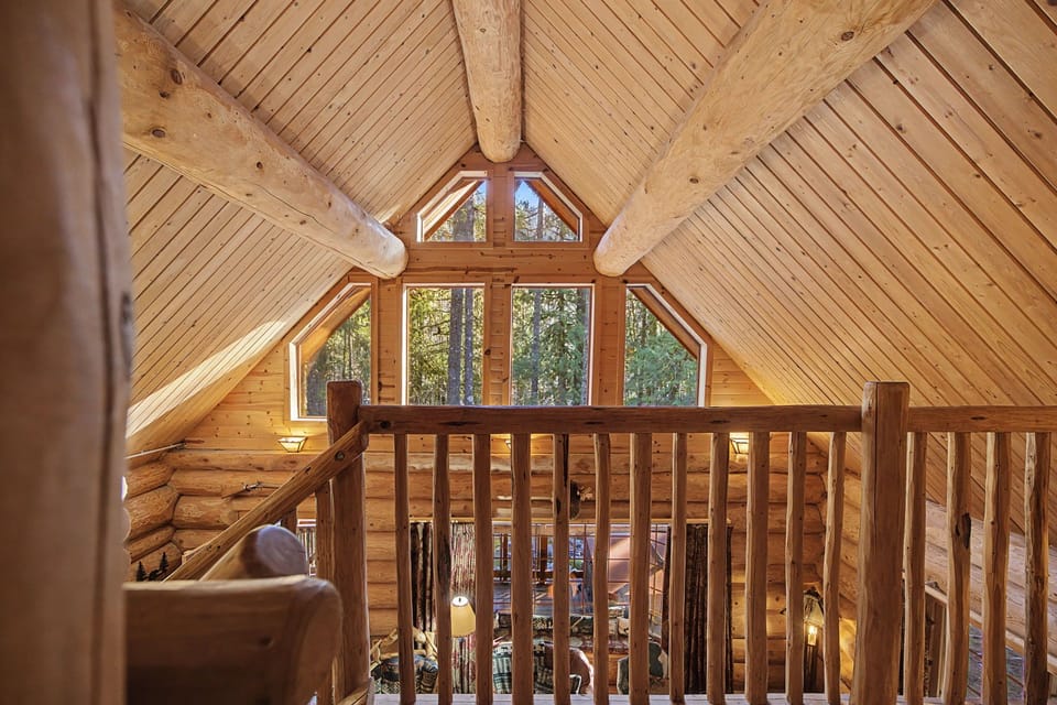 Rustic log cabin loft with soaring timber ceilings and forest views - your perfect retreat for mountain relaxation.