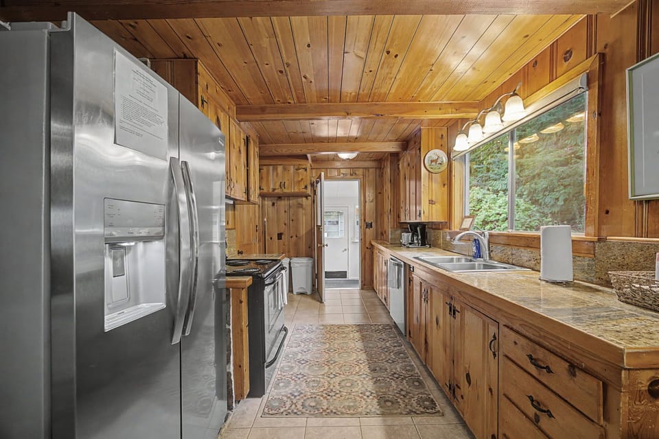 Your rustic kitchen awaits with warm wood cabinets, modern appliances, and charming views that make cooking feel like home.
