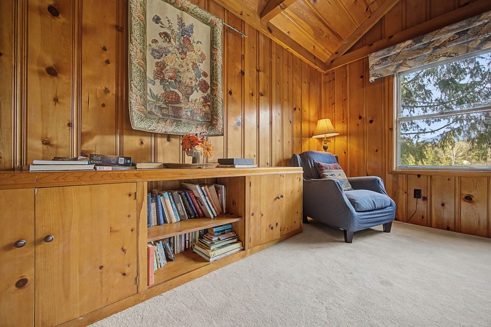 Curl up with a good book in your cozy wood-paneled reading nook, where warm lamplight and forest views create the perfect escape.