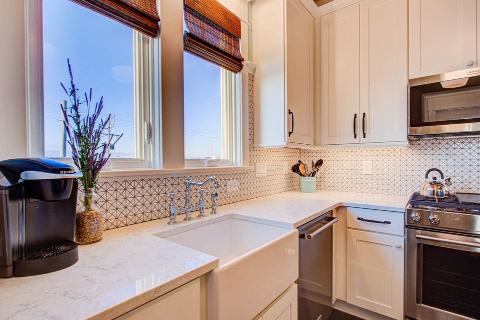 The modern kitchen features stainless steel appliances, a fully stocked prep area, and an island bar with seating for casual meals.